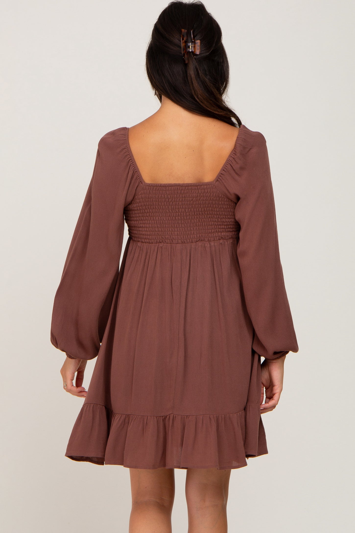 woman wearing a brown smocked back dress with long sleeves and a ruffled hem