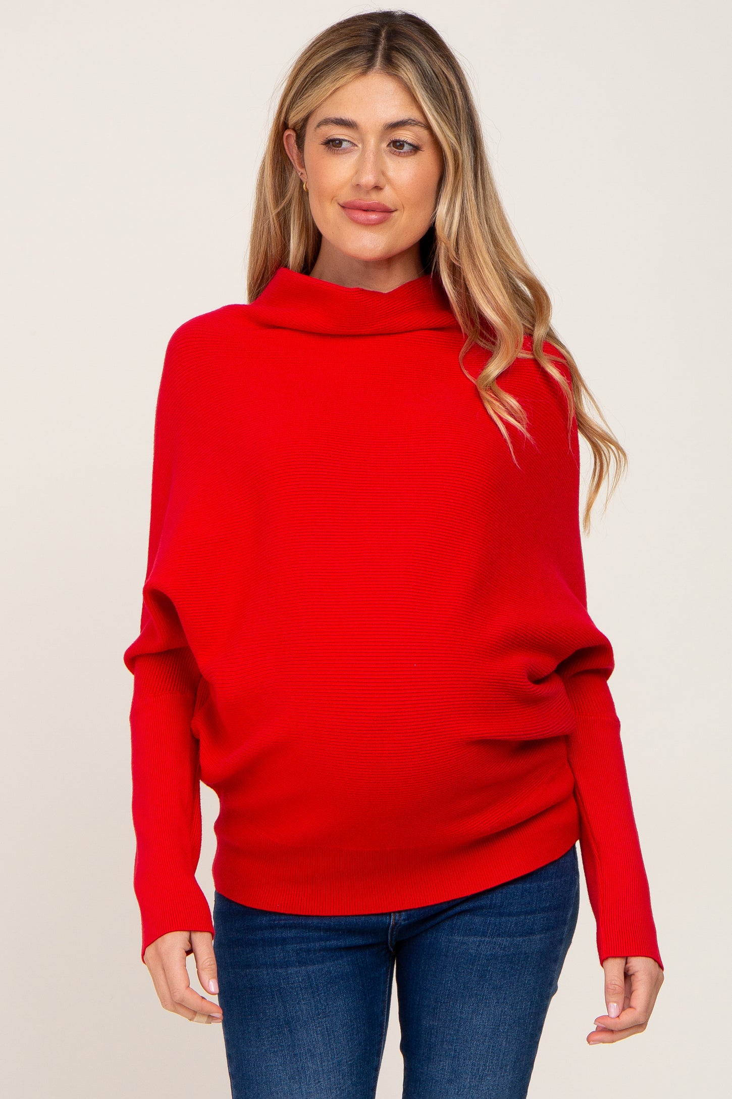 woman wearing a red maternity sweater with a cowl neck and loose fit, highlighting her baby bump