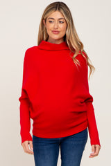 woman wearing a red maternity sweater with a cowl neck and loose fit, highlighting her baby bump