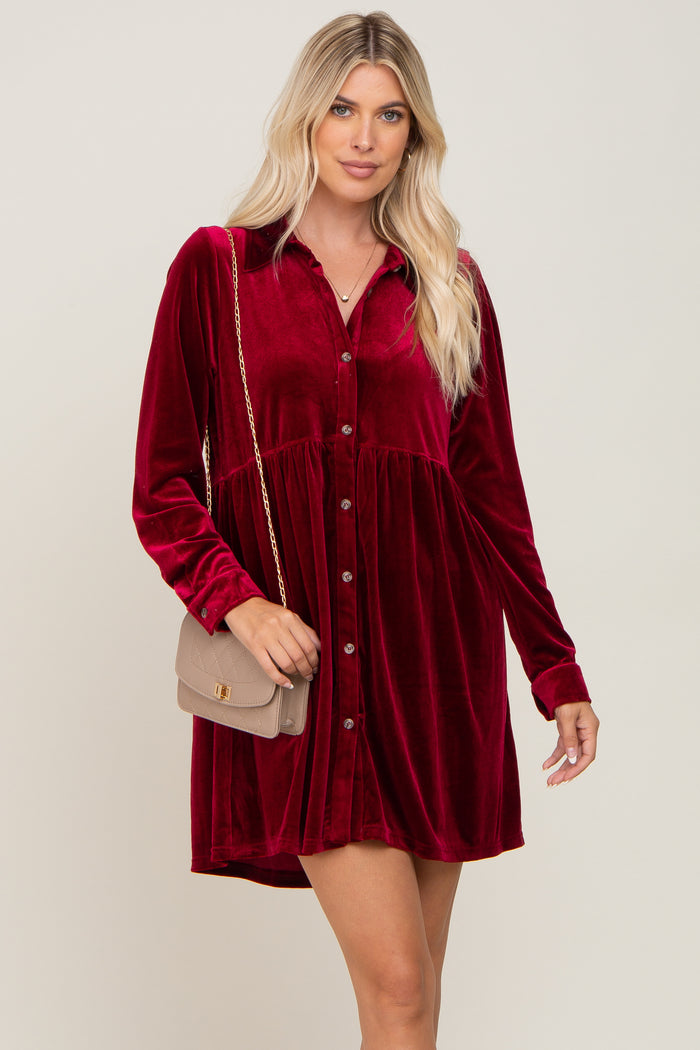 woman wearing a long sleeve burgundy velvet button down mini dress with a tan quilted crossbody bag