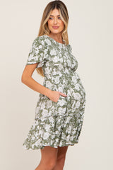 woman wearing a short sleeve green floral maternity dress with pockets and a visible baby bump