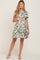 woman wearing a green floral maternity dress with a ruffled hem and holding her baby bump