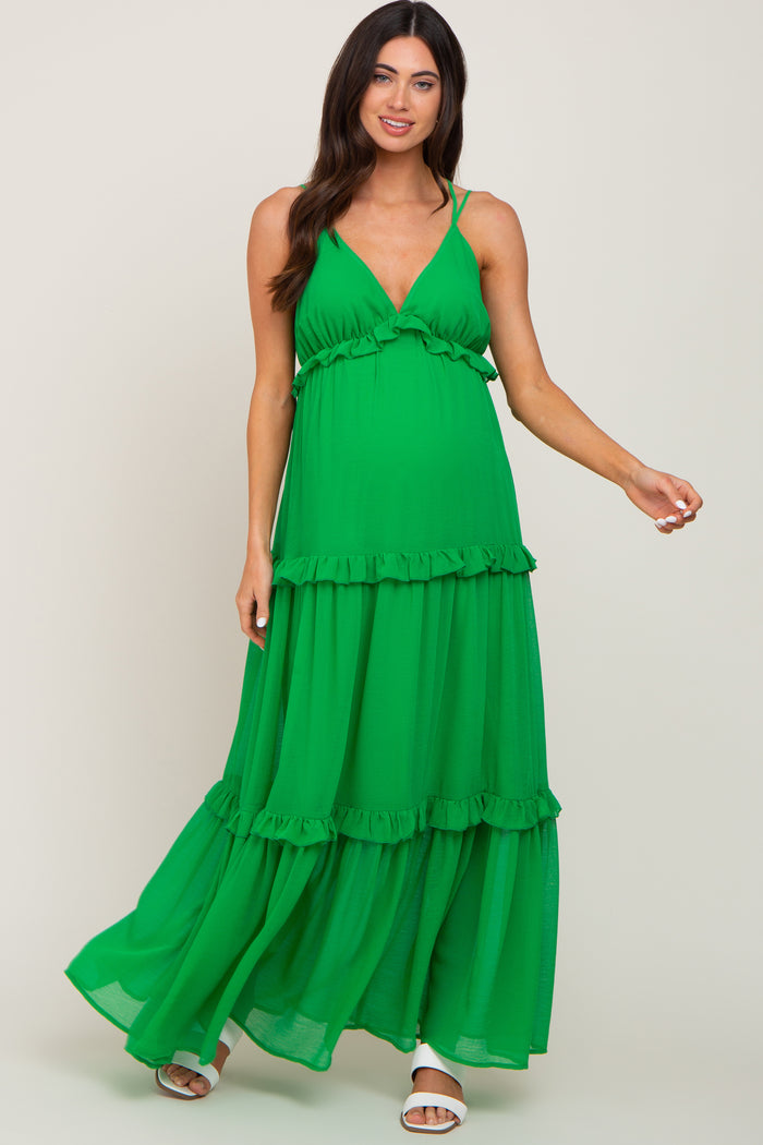 woman wearing a green tiered maternity maxi dress with ruffle details and spaghetti straps