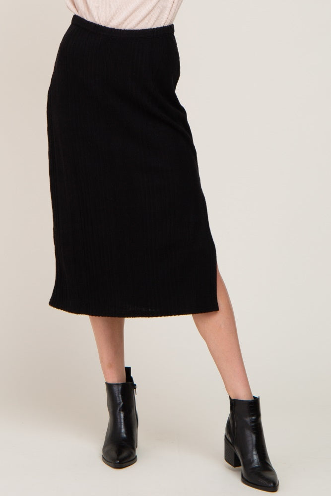 woman wearing a black ribbed midi skirt with a side slit and black leather ankle boots