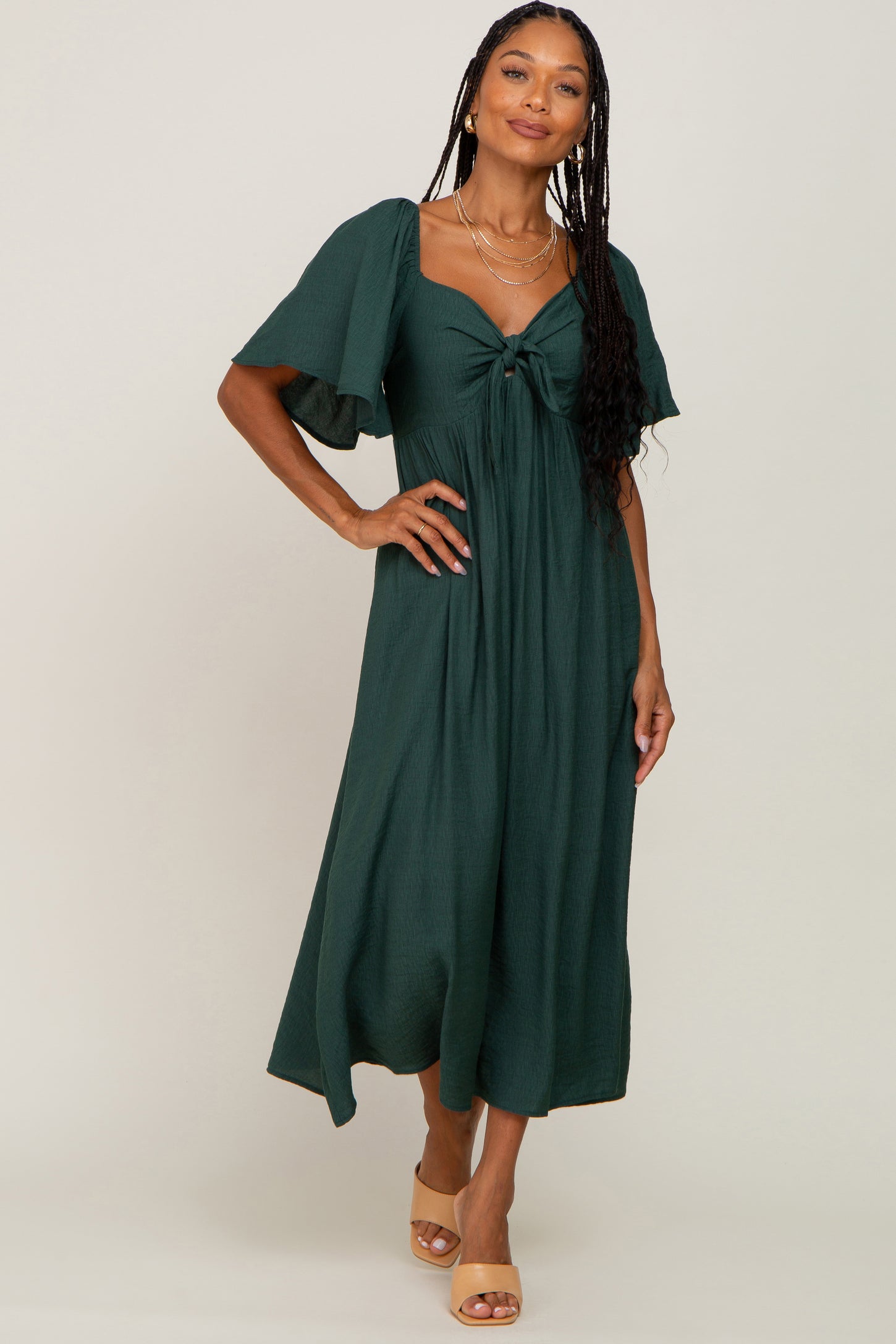 woman wearing a dark green midi dress with short flutter sleeves and a front knot detail