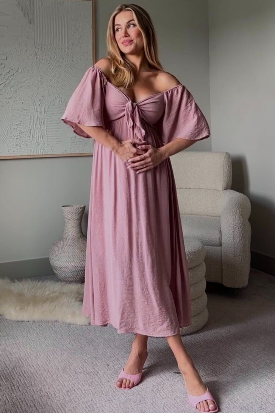 woman wearing a mauve off-the-shoulder midi dress with flutter sleeves and tie-front detail