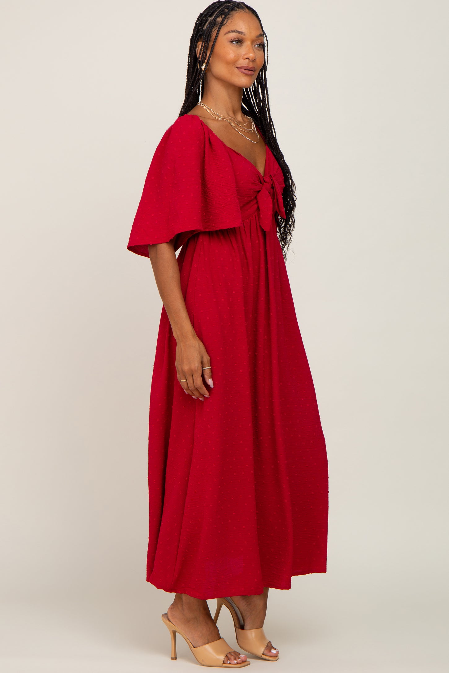 woman wearing a red swiss dot maternity maxi dress with flutter sleeves and a tie front