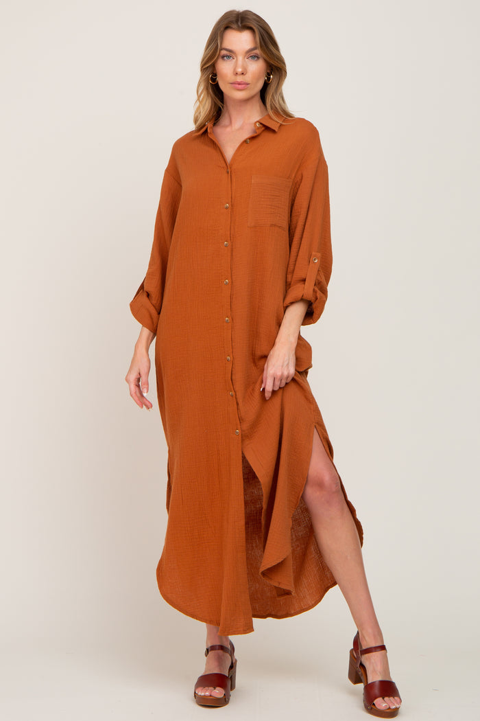 woman wearing a long rust orange button down shirt dress with side slits and brown platform sandals