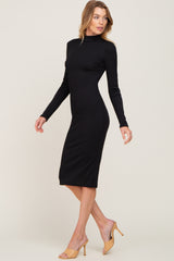 woman wearing a black long sleeve bodycon midi dress with a high neckline and strappy beige heels