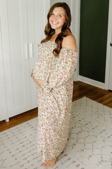 woman wearing a floral off-shoulder maxi maternity dress and holding her baby bump