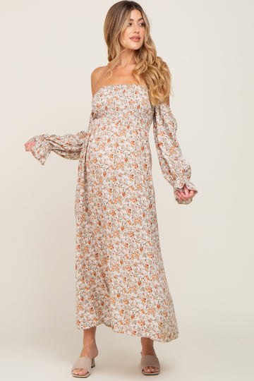 woman wearing a floral off-shoulder maternity maxi dress with long sleeves and a baby bump visible