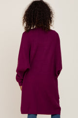 woman wearing a long, deep purple cardigan with oversized sleeves, shown from the back