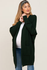 woman wearing a green open-front maternity cardigan with pockets and a visible baby bump
