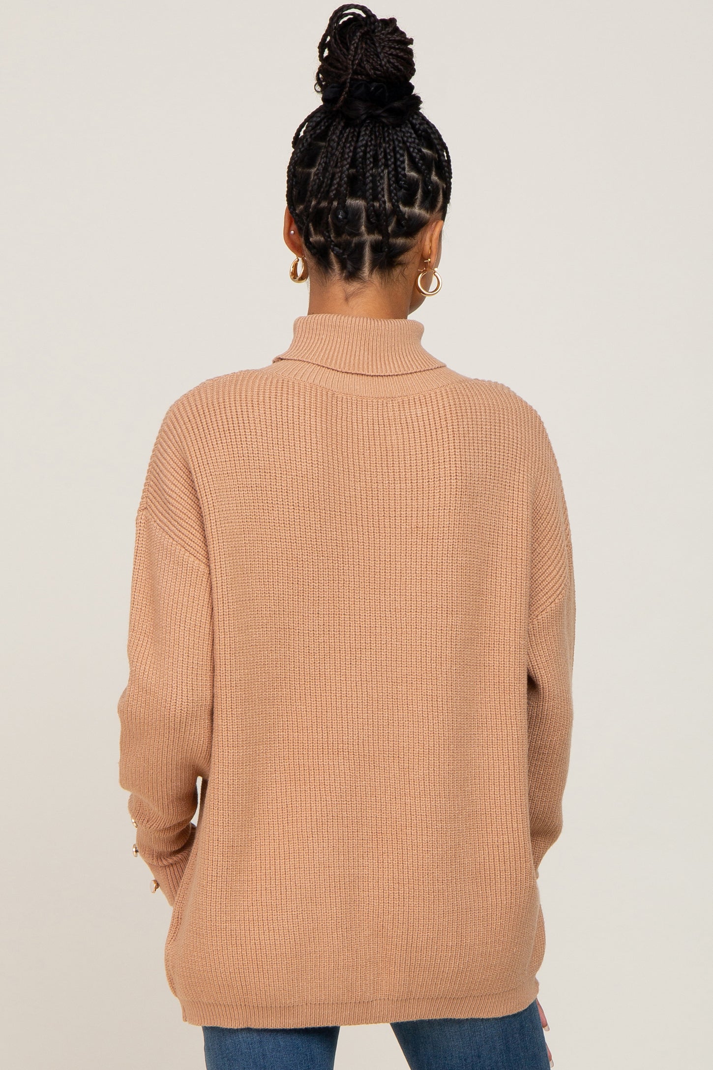 woman wearing a tan ribbed sweater with a high neck and long sleeves, viewed from the back