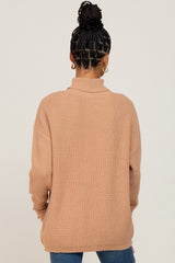 woman wearing a tan ribbed sweater with a high neck and long sleeves, viewed from the back