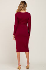 woman wearing a burgundy long sleeve fitted maternity dress from the back