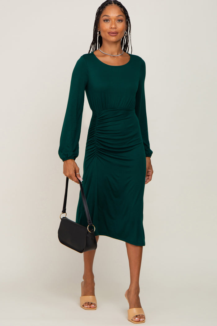 woman wearing a long sleeve dark green ruched midi dress holding a black handbag