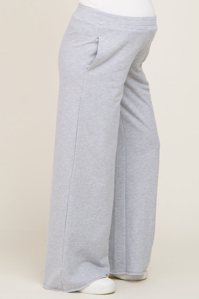 pregnant person wearing grey wide leg maternity sweatpants with pockets and white sneakers