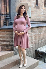 pregnant woman in mauve long sleeve maternity dress and wide brim hat standing on stone steps
