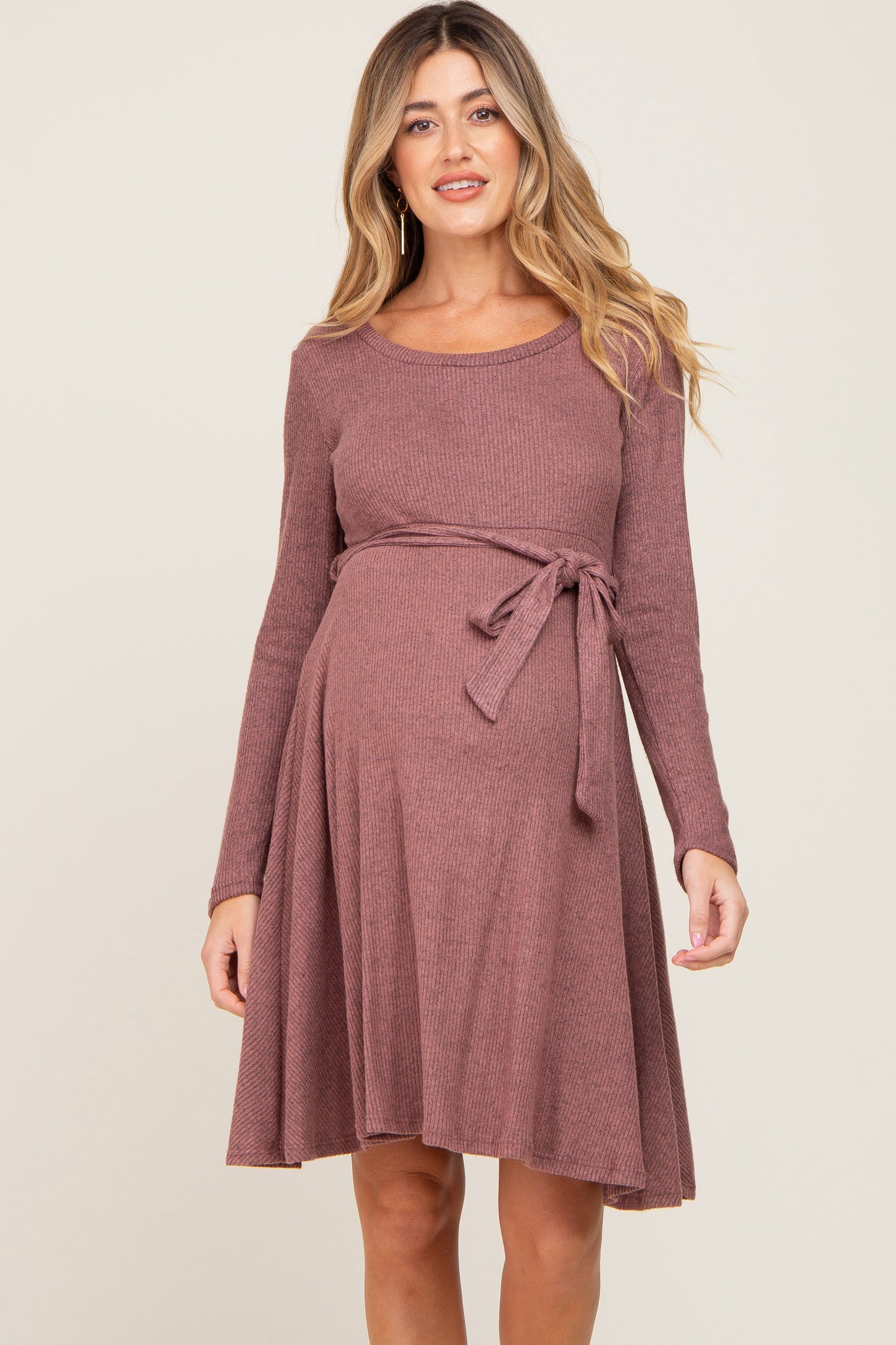 woman wearing a mauve long sleeve maternity dress with a tie waist and a visible baby bump