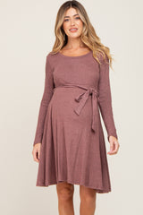 woman wearing a mauve long sleeve maternity dress with a tie waist and a visible baby bump