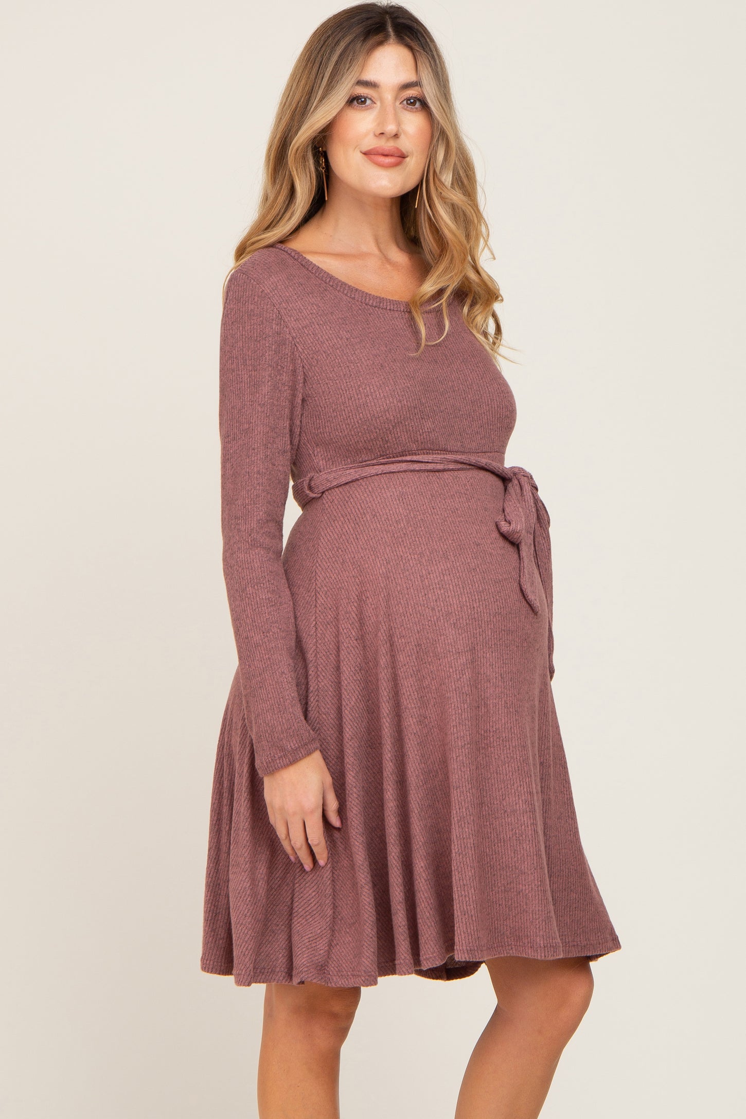 woman wearing a dusty rose long sleeve maternity dress with a tie waist and a visible baby bump