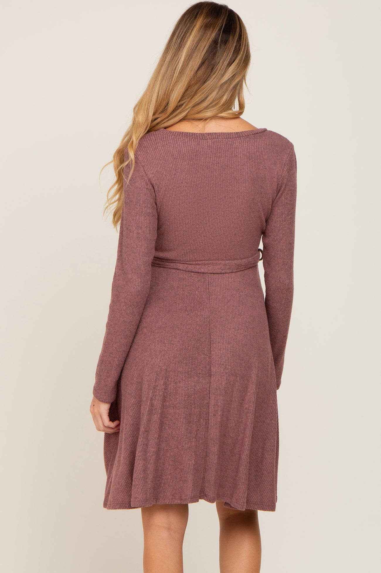woman wearing a mauve long sleeve belted maternity dress, showcasing a flowy skirt and back view