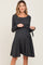 woman wearing a dark gray long sleeve maternity dress with a tie detail at the waist and visible baby bump