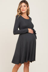 woman wearing a charcoal gray long sleeve maternity dress with a tie belt and visible baby bump
