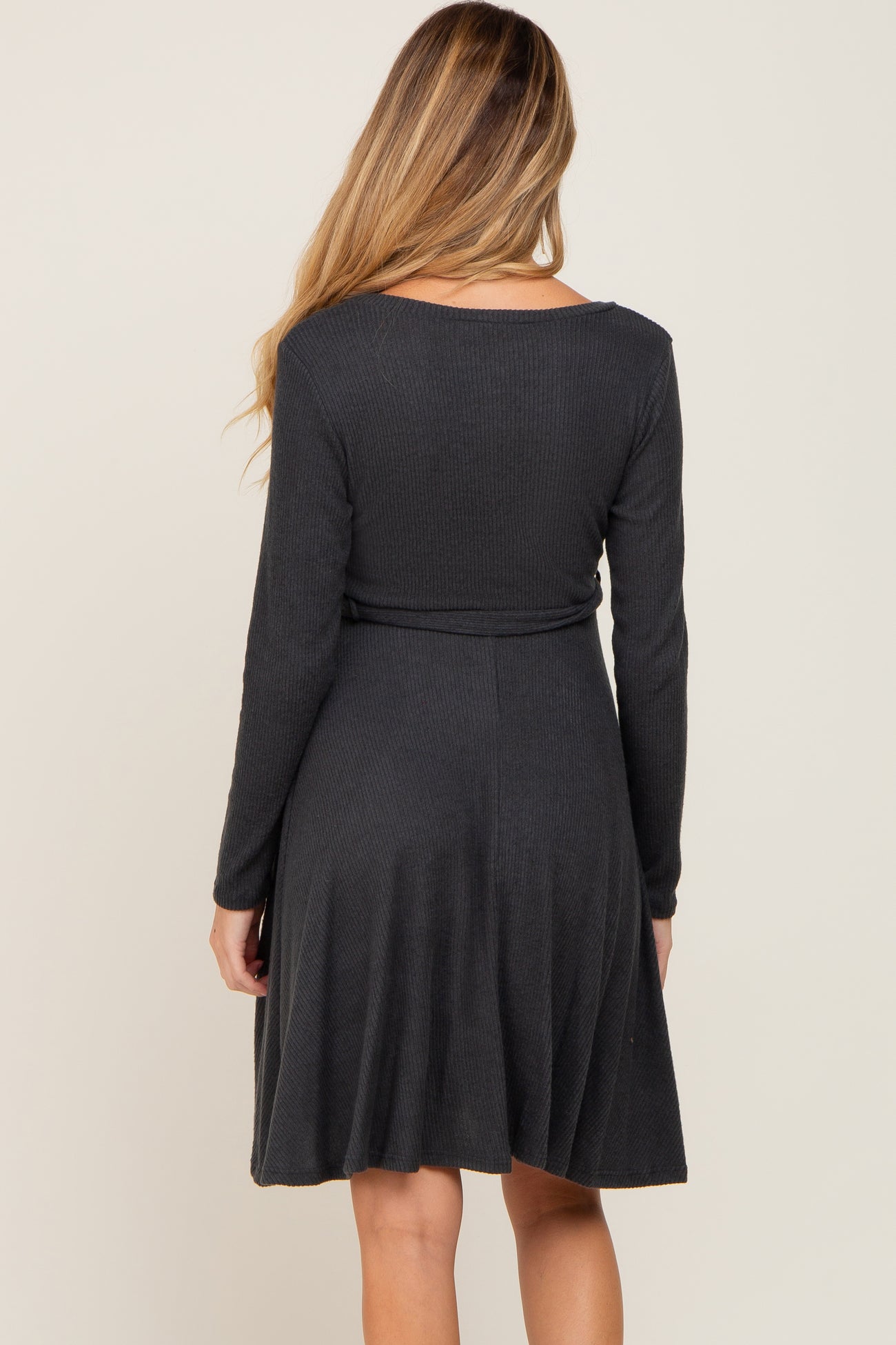 woman wearing a dark gray long sleeve maternity dress with a fitted bodice and flared skirt