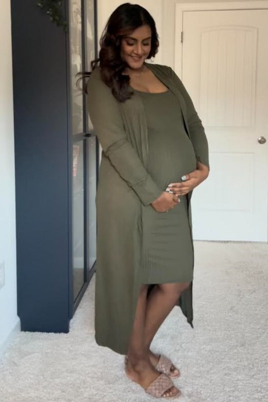 woman wearing a dark olive green maternity dress with a matching long cardigan and showing her baby bump