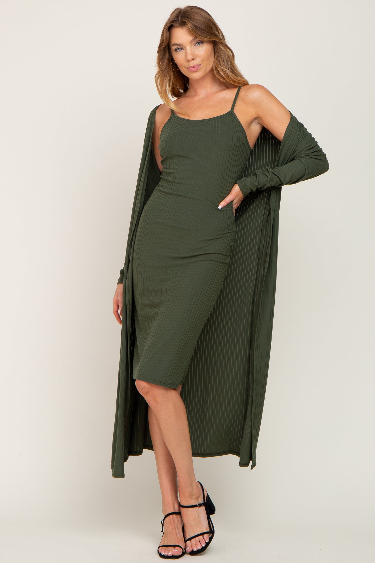 woman wearing an olive green ribbed midi dress with a matching long cardigan and black strappy heels