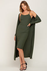 woman wearing an olive green ribbed midi dress with a matching long cardigan and black strappy heels