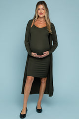 woman wearing an olive green maternity dress with ribbed texture and a side slit, holding her baby bump