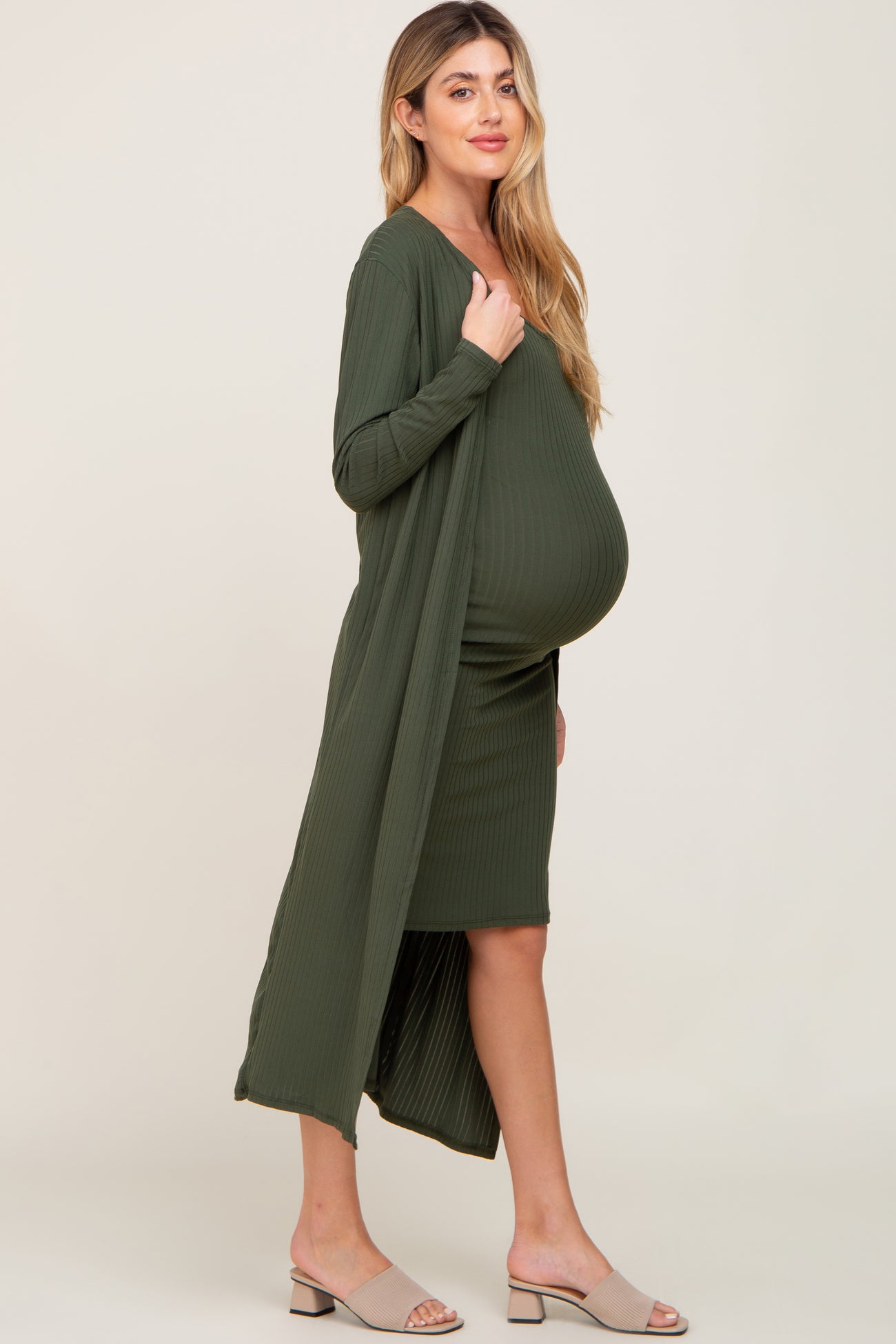 woman wearing a dark green maternity dress with a matching long cardigan and visible baby bump