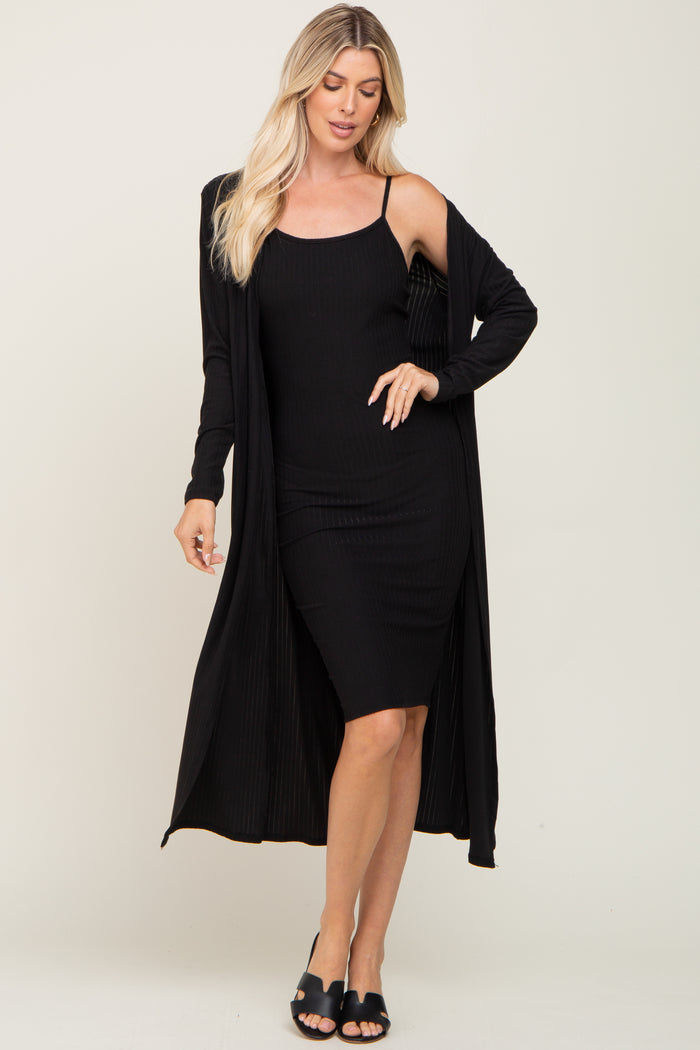 woman wearing a black ribbed tank dress with a long black cardigan over it and black slide sandals