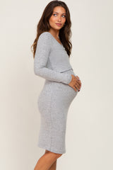 woman wearing a grey long sleeve maternity dress and holding her baby bump