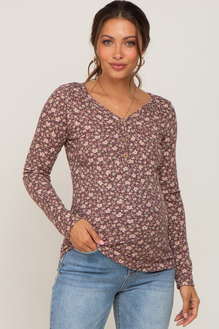Woman wearing a purple floral long sleeve maternity henley top and light wash jeans
