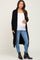 pregnant woman wearing a long black cardigan white maternity top and blue jeans with black boots