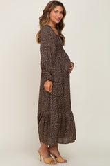 woman wearing a black and mustard floral maternity maxi dress, showing her baby bump with long sleeves and tiered skirt
