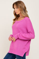 woman wearing a bright pink oversized sweater with long sleeves and side slits, paired with jeans