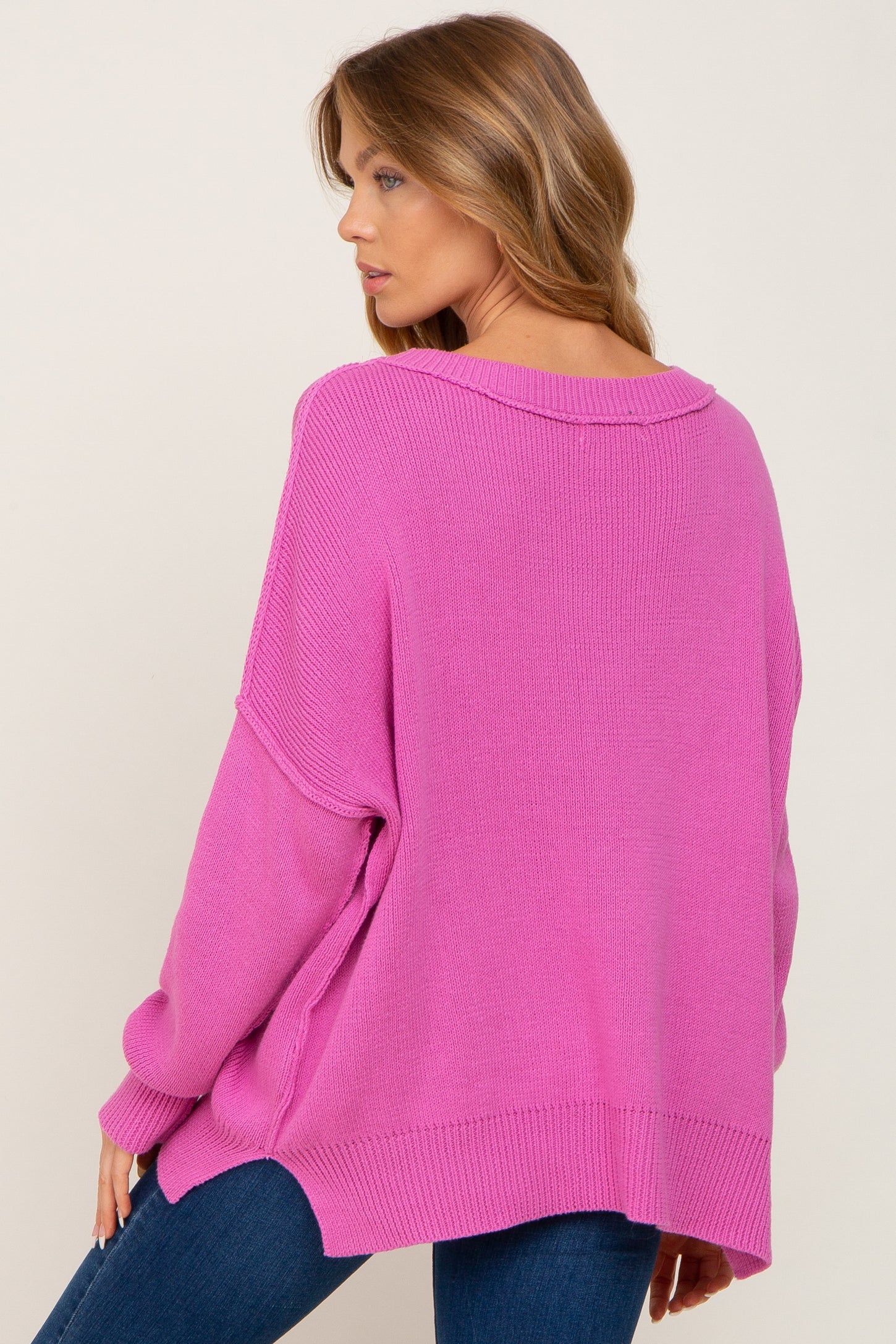 woman wearing a loose-fitting pink oversized sweater with a ribbed texture and dropped shoulders