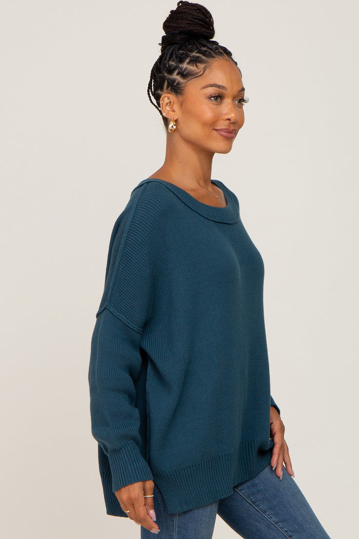 woman wearing a teal oversized sweater with a scoop neck and long sleeves, paired with blue jeans