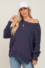 woman wearing a dark purple off-the-shoulder sweater with long sleeves and a relaxed fit, paired with light blue jeans