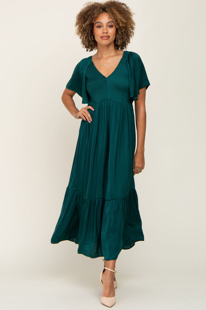 woman with curly hair wearing a dark emerald green v-neck midi dress with flutter sleeves and tiered skirt