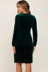 woman wearing a green velvet long sleeve maternity dress, shown from the back