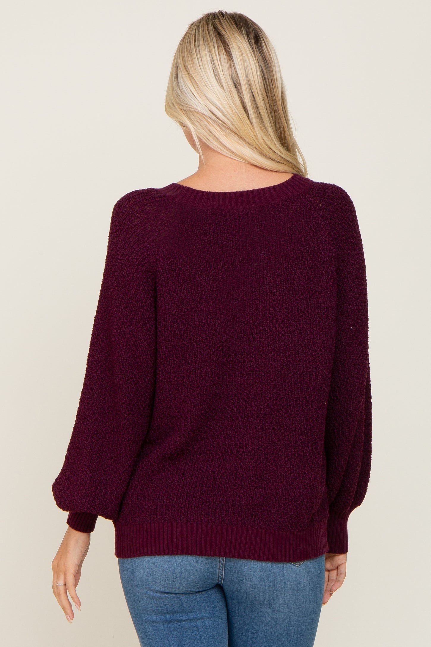 woman wearing a burgundy oversized sweater with balloon sleeves, viewed from the back