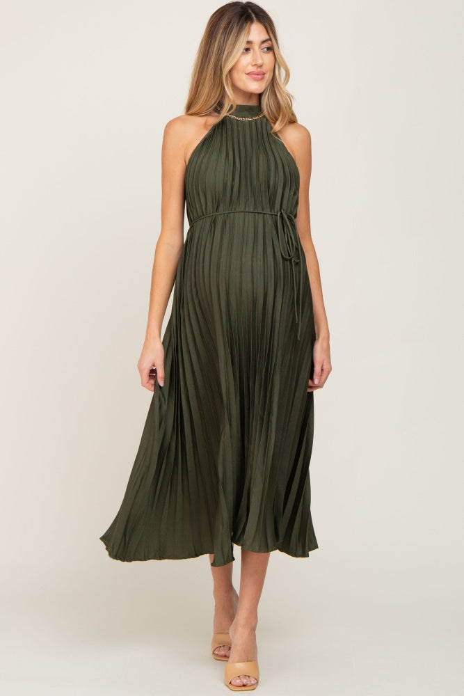 pregnant woman wearing an olive green pleated halter maternity midi dress with a gold chain neckline