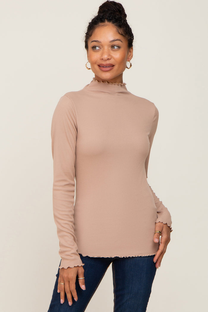 woman wearing a beige long sleeve ribbed top with a mock neck and frill hem details paired with dark jeans