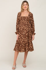 woman wearing a brown floral print maternity dress with a square neckline and ruffle hem